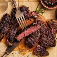 Sliced medium rare grilled Beef steak Ribeye with salt and pepper on meat cutting board on dark wooden background