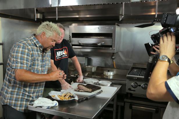 Behind-The-Scenes with Host Guy Fieri About to Taste the Pork Belly Reuben with Chef and Owner Sean Johnson Observing at Meat Southern B.B.Q. and Carnivore Cuisine in Lansing, Michigan as seen on Food Network's Diners, Drive-Ins and Dives episode 2704.