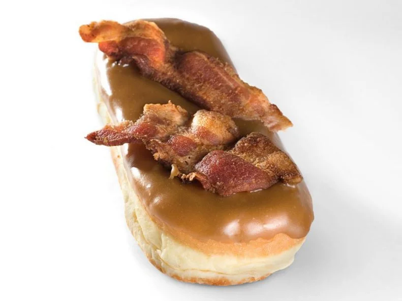Maple and bacon may seem like a standard (albeit exquisite) combination these days. Portlandâ  s Voodoo Doughnut might just be credited for opening the food worldâ  s palate to the joys of sweetened, salty pork in its notorious Maple Bacon Bar. Raised yeast dough is formed into logs and deep-fried to cloudlike consistency. The top is slathered with maple frosting as well as a crisp piece of bacon broken in half, decoratively placed side by side, so that smoky, snappy meat is evenly distributed in each ethereal bite.