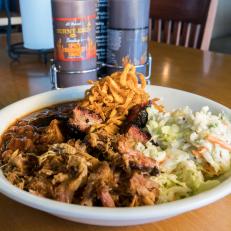 The signature dish of Burnt End BBQ restaurant, The Burnt End Bowl with Pulled Pork, rests on a table inside the restaurant, as seen on The Grill Dads, Season 1.