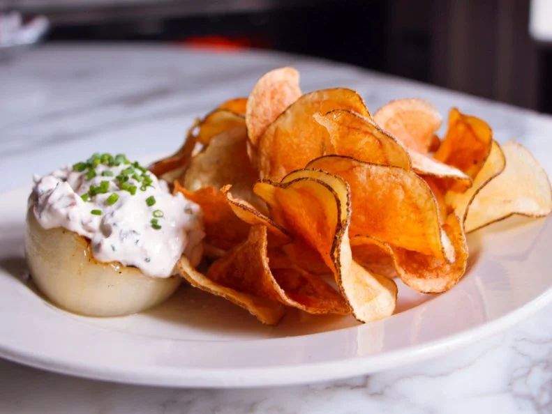 When it comes to dips and sauces, Alabama may be best known for its namesake white barbecue sauce, but there’s a contender vying for unofficial state dip status: Chef Frank Stitt’s charred onion dip. At his causal Italian trattoria, Bottega Café, the celebrated Birmingham chef crafts a sweet and tangy dip to serve with potato chips and pair with aperitifs. Red onions are charred in the wood-burning oven, then blended with sour cream, Worcestershire, Tabasco and freshly ground pepper until creamy. The smoky, addictive dip is served in a hollowed-out onion with a topping of freshly snipped chives and a side of house-made potato chips for scooping.