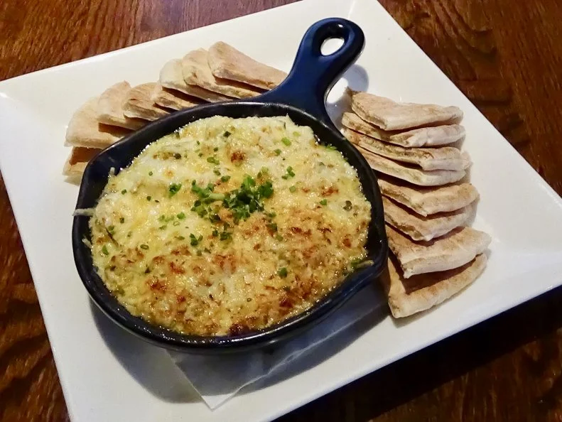With Delaware’s proximity to the Delaware and Chesapeake Bays, its restaurants lean into seafood, offering crab in many preparations, including crab dip. Buckley’s Tavern has cemented its status as a Delaware institution thanks in large part to its fan-favorite crab-spinach-artichoke dip. The combination stars sweet blue crab meat combined with spinach, artichoke hearts, cream cheese, sour cream, lemon juice and a pinch of Old Bay, a key component in any Mid-Atlantic crab dish. The mixture is baked with a Parmesan topping and served hot with warm pita wedges. Rich and savory, the dip will transport you to the beach, even if you didn’t grow up cracking crab legs at seaside family gatherings.