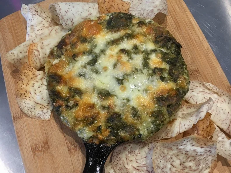 Hot, bubbly spinach-cheese dip is nearly universally satisfying, so when Chef Lee Anne Wong created her Luau Cheese Dip as a regular special for her Honolulu brunch spot, Koko Head Café, she put a Hawaiian spin on it, pulling in steamed kalo (or taro plant) leaves, which she describes as an earthier-tasting spinach. Kalo, one of the most important foods in Hawaiian culture and cuisine, was traditionally baked in an underground oven and pounded to make poi. For her version, Wong peels then pressure-steams kalo, removes the cooked, sticky outer layer and pounds only the starchy core, slowly adding water to achieve a loose consistency. The poi is mixed with steamed, chopped kalo leaves, cream cheese, mayonnaise and shredded Vermont white cheddar, plus an arsenal of flavor bombs like caramelized Maui sweet onions, Worcestershire sauce and fish sauce. The mixture is broiled in a mini cast-iron skillet and served with crispy kalo chips, like Hawaii’s kale chips.
