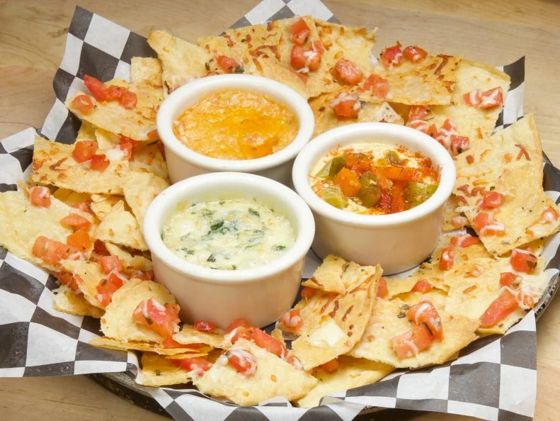 Chicago institution Lou Malnati’s Pizzeria is lauded for Chicago deep-dish pizza — but good pies take a while to bake. Since each pie takes about 30 minutes to arrive at the table, the Malnati family added a chips-and-dip appetizer to the menu to tide diners over. The crisp, cheese-topped pizza chips are made from the family’s prized pizza dough, and are served warm with a trio of dips: roasted garlic, cheesy artichoke and giardiniera-topped hummus. Giardiniera, a hot-and-tangy Italian pickled relish of peppers, cauliflower, carrots and green olives, is an integral part of Chicago cuisine, owing to the city’s deep Italian roots. It’s typically eaten atop Italian beef sandwiches or as part of an antipasto spread, but here, the giardiniera adds kicky zest to classic hummus; some diners order extra to make their pizza zing, too.