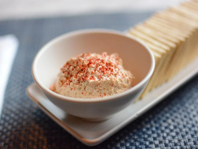 Louisiana native Donald Link grew up visiting family in Southern Alabama and taking trips to the Florida coast, so it’s fitting that Peche, his seafood-centric New Orleans restaurant, celebrates the flavors and foodways of the entire Gulf coast. Link’s Smoked Tuna Dip is reminiscent of the ones he enjoyed at Gulf Coast fish shacks throughout his childhood, but he adds extra Southern flair by gently smoking Gulf-caught tuna over pecan and oak woods in the restaurant’s smoker until just cooked through. The tuna is then shredded with forks to retain texture, and folded with Creole mustard, mayonnaise, sour cream and Cajun spices. The creamy, smoky dip is served with Saltines, the unofficial table cracker of NOLA seafood restaurants.