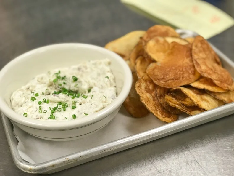 At The Lakewood in Durham, the seasonal menu proudly showcases North Carolina products and the farmers and producers who make it possible. North Carolina’s coastal state designation means that seafood figures prominently, as with the smoked North Carolina bluefish dip. North Carolina bluefish, which Chef Phoebe Lawless sources from Locals Seafood, is prized for its flaky texture, rich flavor and medium oil content, making it ideal for smoking. The cold-smoked fish is flaked and folded with crème fraîche and a flurry of fresh dill and parsley; the result is served with house made potato chips. The blue fish season runs from late summer to fall, so Lawless buys as much as possible to smoke for savoring well past the season.