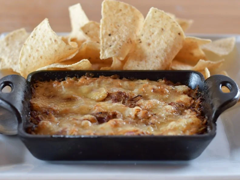 Besides excelling at brewing, Lineage Brewing aims to unite Columbus locals and visitors over a pint and stepped-up pub grub, with dishes like the popular Reuben Dip. General manager and Ohio native David Day was inspired by memories of his grandma’s Saturday corned beef dinners and his dad’s signature Sunday Reubens, a corned beef sandwich with Swiss, sauerkraut and Russian dressing on rye bread. The dip gives the sandwich components a gourmet upgrade, starring brined brisket that braises in Lineage Brewing beer. It’s shredded and combined with Russian dressing (made with cream cheese instead of mayo, for heft) and house-made sauerkraut (using local cabbage). The mixture is heaped into a cast-iron casserole dish, topped with cave-aged Swiss cheese, sprinkled with caraway seeds and baked until bubbly and golden and ready for tortilla-chip dunkers.