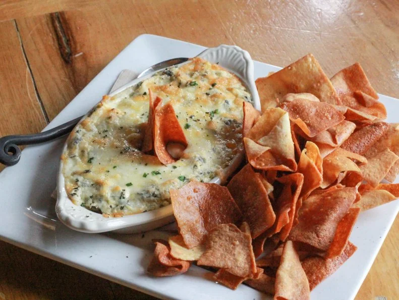 Spinach-artichoke dip is a nationwide favorite, but at The Skinny Pancake in Burlington, the dip is elevated to the best version of itself with a triple dose of Vermont dairy. Cream cheese is responsible for the velvety texture, Cabot cheddar for its signature gooey stretch and half-and-half for its over-the-top richness. The cheesy mixture is blended with local spinach, artichokes, garlic and house hot sauce crafted from local hot peppers. The chunky dip is topped with more Cabot cheddar, baked until bubbly, and served piping hot with fried chips made from squares of the restaurant’s savory crepe shells.