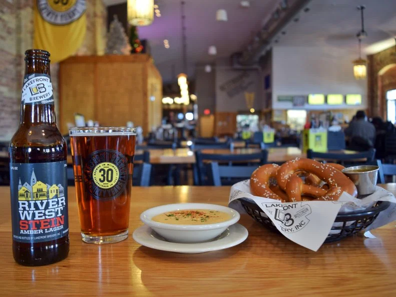 Wisconsinites are serious about their cheese â   Green Bay Packers fans are known as cheeseheads â   but theyâ  re just as serious about their beer. The pride-of-Wisconsin foods come together in beer cheese soup, a dish thatâ  s ubiquitous on restaurant menus across the state. Beer cheese also makes a fine dip, like at Milwaukeeâ  s Lakefront Brewery, where itâ  s paired with local beer-coated soft pretzels. The silky dipping sauce features five Wisconsin-made cheeses, including aged cheddar, nutty Gruyere, Parmesan, smoky Gouda and Swiss, all blended with sour cream, cream cheese and their flagship Riverwest Stein amber lager, for hoppy bitterness and malt sweetness. The kitchen goes through 80 pounds of cheese per week and makes a 10-gallon batch of beer sauce every other day.