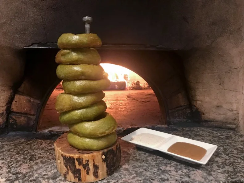 Jackson Hole landmark Snake River Grill does the Cowboy State proud with its menu of American classics with a twist, including the centerpiece-worthy Green Chile Onion Rings stacked on a branding iron â  ring rod.â   The rings are dipped in a beer batter bolstered by whipped egg whites (for a crunchy exterior and airy interior) and pureed basil, cilantro and green chiles, which give the rings their trademark green color. It makes for a dramatic presentation, but itâ  s the warm mustard-beer dip that quietly steals the show. The rings are so big that the kitchen only gets two slices out of every sweet onion, so the leftover onions are caramelized then pureed for dip with spicy dark mustard, apple cider reduction and locally brewed Snake River Brewery Pale Ale.