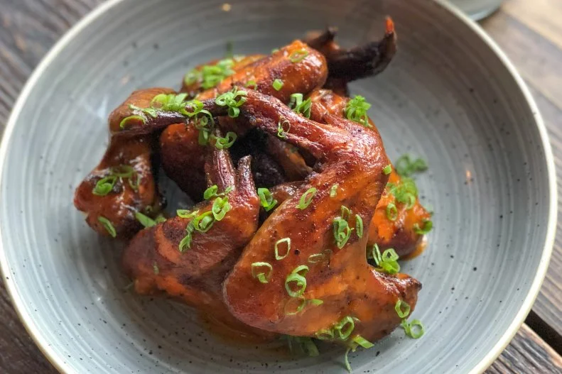This Atlanta restaurant is all about appealing to the urban explorer, with its vast outdoor space and indoor mess-hall look. The folks here may not take themselves too seriously, but they are definitely serious about their wings. The wings are first covered in their own house chicken rub with flavors of brown sugar, garlic and paprika, before they are put into the smoker with oak and cherry woods. The wings are then fried and tossed in a special bourbon-barrel peach sauce made with bourbon, house hot sauce, gochujang, Dr. Pepper and a local peach jam. They're topped with scallions and served with crudites and housemade blue cheese dressing.