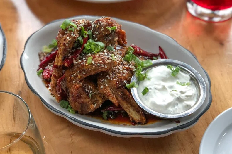 Everything bagels may have started the "everything" craze, but these wings at Mott Street take the spice blend to a whole new level. The crisp wings are glazed with a sweet and spicy mix of soy, jaggery and dried chiles and topped with sesame and poppy seeds and fried shallots. To cool it all down, tzatziki is served on the side.