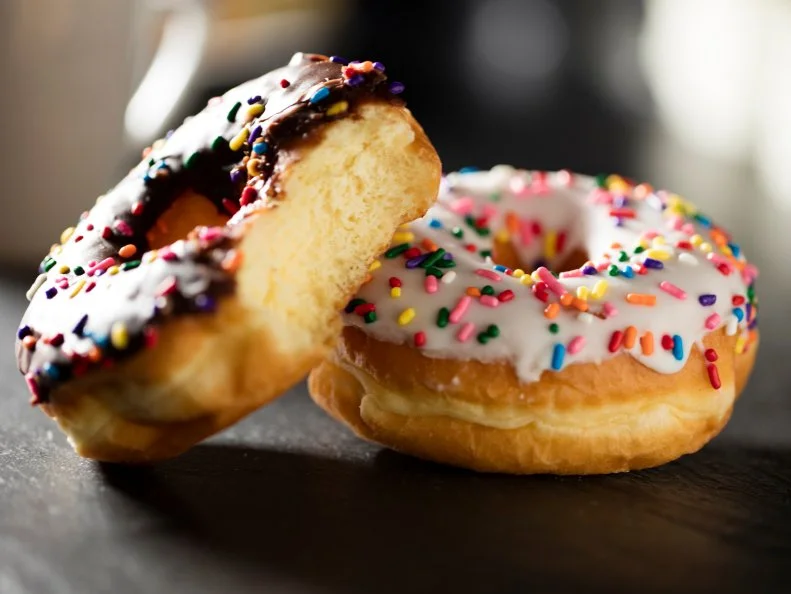Two doughnuts, one chocolate - one vanilla, with sprinkles