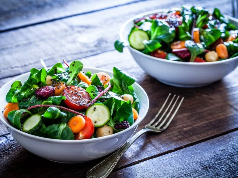 Two healthy salad bowls with chia seeds shot on rustic wooden table. The ingredients included for the preparation are chia seeds, lettuce, cherry tomato, carrot, arugula, cucumber and avocado. DSRL studio photo taken with Canon EOS 5D Mk II and Canon EF 100mm f/2.8L Macro IS USM