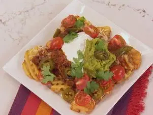 Nacho French Fries was prepared by Food and Lifestyle Expert Brandi Milloy. She takes half of a 20 oz. bag of frozen french fries, cooks them according to the package, and places them onto a platter. She first layers the fries with prepared chili from the can. Next add montary jack cheese, salsa, and a few cherry tomatoes. Add sour creme and pickled jalepenos, finishing it off with some cilantro, as seen on Let's Eat, Season 1.