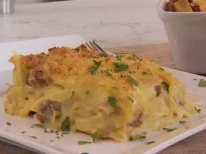Pasta Pierogi Lasagna was prepared by Chef Stuart O'keeffe. He begins with leftover mashed potatoes that he has heated up. He then adds 1 lb. of ground beef and 8 oz. of italian sausage to a pan and begins to cook them together. While Food and Lifestyle Expert Brandi Milloy cooks the meat of the stove, Chef Stuart O'keeffe makes a roux by melting butter in a warm pan. Once it starts to melt, add and whisk together 4 tablespoons of flour and 4 tablespoons of butter. After it has combined, add in warm milk, stirring as you pour. Whisk together until the mixture thickens. Add in sharp cheddar cheese and mix, seasoning with salt and pepper. Pour a layer of the roux on the bottom of the casserole pan. Next add noodles on top of the roux layer. Food and Lifestyle Expert Brandi finished cooking the meat, removed it, and began to cook the cabbage in the pot. She then added the meat back into the cabbage and combined. Layer the meat and cabbage layer on top of the noodles, then mashed potatoes, then the cheese roux, and repeat. Finish with parmesan cheese and cook for 30-40 minutes on 375 degrees, or until golden brown. Remove, cut, and serve, as seen on Let's Eat, Season 1.