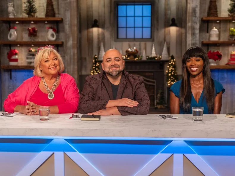 Judges Nancy Fuller, Duff Goldman, and Lorraine Pascale pose for a photo at the judges table, as seen on Holiday Baking Championship, Season 5.