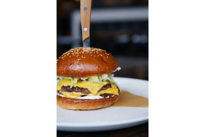 Named for a Prohibition-era Detroit River rum runner, this sleek Brush Park spot focuses on "cuts and cocktails," according to co-executive chefs Joe Giacomino and John Vermiglio. The adult-beverage list is expansive, and the meat is top-notch. That's why the burger here is so darn good. It features two 4-ounce flat-top-griddled patties made from a custom blend of chuck, brisket, short rib and dry-aged rib eye. Each one is topped with a slice of American cheese. Iceberg lettuce and housemade shallot pickle mayonnaise (and fried egg for those who want some runny yolk) are layered within the sesame seed bun.
