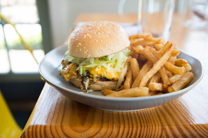 John T. Edge of Southern Foodways Alliance literally wrote the book on Hamburgers & Fries. So, when the folks at Hog & Hominy got to talking with him about what sort of classic burger they'd serve to their late-night crowds, they heeded his advice to try an Oklahoma City onion burger. The Depression-era creation uses griddled onions to stretch out pricey ground beef. The John T Burger features locally sourced Black Angus ground beef that's shaped into a 5-ounce ball, pressed on the flat top with thinly sliced onions and doused with several layers of secret seasoning. It's shingled with three slices of American cheese and griddled until the cheese has crisped, then topped with thinly sliced, pickle juice-dressed lettuce on a griddled bun with mustard.