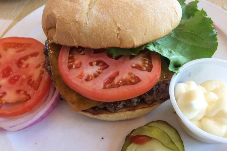 There aren't many reasons to travel to the tiny town of Siler City, a 30-minute drive from both Greensboro and Chapel Hill, yet burger aficionados come from all over the state to sink their teeth into Johnson's Drive-In's delicious cheeseburgers. Second-generation owner Claxton Johnson handpicks the marbled beef that he grinds into thick rounds that are pressed down on a sizzling hot griddle. Each one is topped with a thick slab of Velveeta cheese that melts into the meat, placed in a bun and slung across the lunch counter straight to adoring (and occasionally drooling) fans, who make sure to arrive before Johnson sells out of burgers for the day.