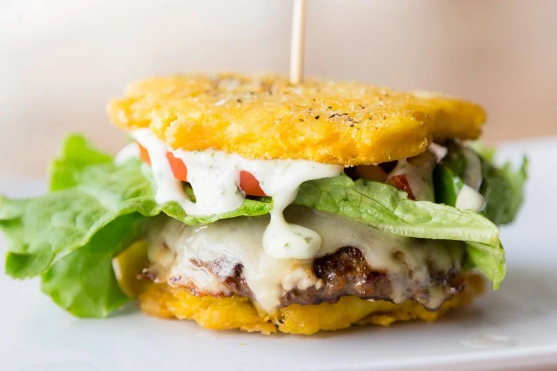 Blending South Florida burger culture with Venezuelan comfort food, Pincho Factory's Toston Burger is a hand-held riff on pabellón criollo, the traditional Caribbean plate of shredded beef, black beans, rice and fried plantains. At this fast-casual mini-chain, those fried plantains are swapped out for tostones, which are made from the unripe, greener version of the fruit. They are fried once, pressed into discs, then fried again until crisp. Those crunchy rounds serve as the bun for the 5-ounce all-beef patty topped with melted white American cheese, lettuce, tomatoes and housemade cilantro and roasted garlic sauces.