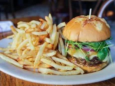 This New York City minichain of bistros recently made its way down to the District, bringing along its farmer-focused fare and laid-back vibe. At its lively Penn Quarter locale, just steps from Capital One Arena, Executive Chef Brian Ellis serves a truly supreme burger creation. His Burger Supreme includes a pepper-crusted patty made from a dry-aged short rib blend, topped with nutty raclette cheese, spicy watercress and red onion, drizzled with a green peppercorn sauce and tucked inside a Gruyère bun. It comes with a side of fries, perfect for soaking up all the leftover juice and peppery sauce that pools on the plate.