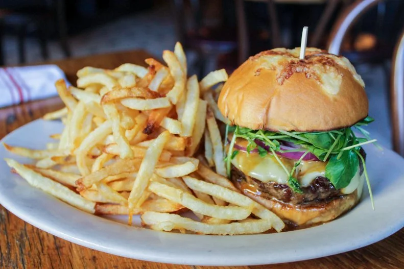 This New York City minichain of bistros recently made its way down to the District, bringing along its farmer-focused fare and laid-back vibe. At its lively Penn Quarter locale, just steps from Capital One Arena, Executive Chef Brian Ellis serves a truly supreme burger creation. His Burger Supreme includes a pepper-crusted patty made from a dry-aged short rib blend, topped with nutty raclette cheese, spicy watercress and red onion, drizzled with a green peppercorn sauce and tucked inside a Gruyère bun. It comes with a side of fries, perfect for soaking up all the leftover juice and peppery sauce that pools on the plate.