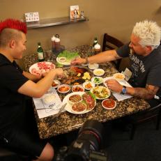Behind the scenes: host Guy Fieri and owner/chef Joe Kim of Dae Gee Korean BBQ in Denver, CO cook the beef bulgogi on the built in grill, as seen on Food Network's Diners, Drive-Ins and Dives, Season 23.