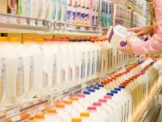Woman checking ingredients on back of milk carton in supermarket