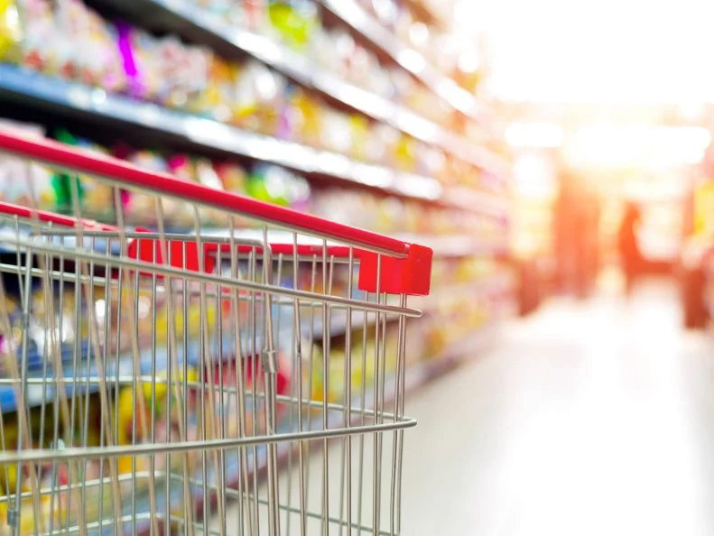 Supermarket interior, empty red shopping cart.