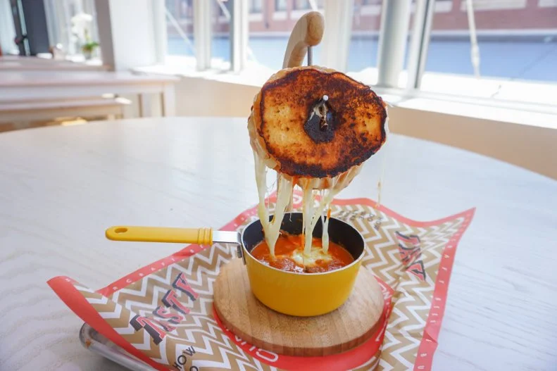 Everyone loves a good mashup, so why not one between a grilled cheese and a doughnut? At this beer-focused spot with multiple NYC locations, a freshly glazed doughnut is sliced in half and filled with melty mozzarella cheese. It's then hung on a banana stand over a steamy bowl of tomato soup. The cheese oozes into the soup, making for a creamy texture and the perfect photo op.