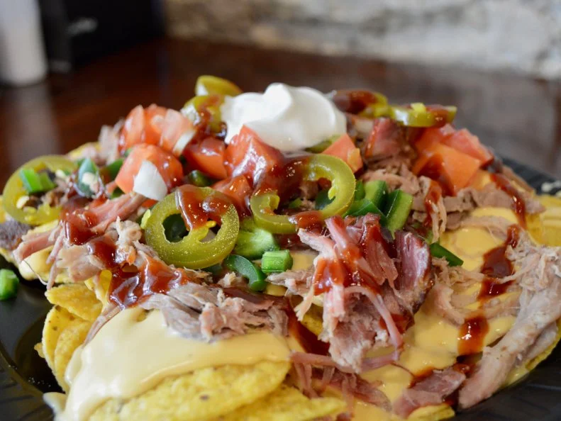 Kansans know good barbecue, and HHB BBQ in Downtown does it well. Pit master and owner Ed Moege fires up the outdoor smokers early in the morning to start making his Topeka-style ‘cue. His pulled pork nachos are a popular choice. Moege tops the tortilla chips with a mound of smoked pulled pork, then smothers the lot in silky cheese sauce. You get to put on the rest of the toppings yourself, so skip the salsa and go for the housemade barbecue sauce instead. Round out your order with a cold draft beer to balance all that cheesy, porky richness.