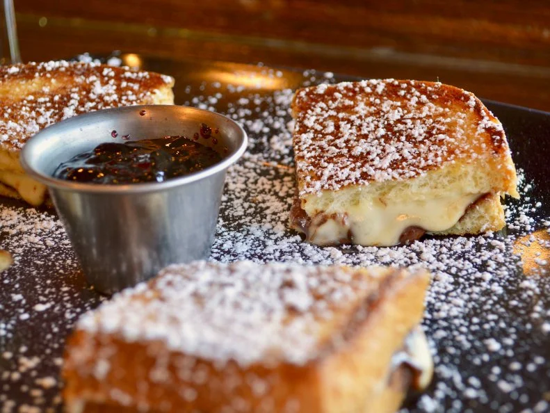 Wheel = cheese. Barrel = craft beer. Both feature prominently on the menu at this cozy restaurant in the North Topeka Arts District (NOTO). Chef Erin Fowler puts a grilled-cheese spin on some classic sandwiches, such as the Monte Cristo (made with brie and Swiss) and the Olga (a twist on a classic Reuben). She also creates grilled-cheese desserts, like the Not So Bittersweet Symphony. This dish starts with a hefty slice of brioche, which is slathered with creamy brie and chocolate hazelnut, then toasted. A dusting of powdered sugar amps up the richness. Dip the bread into the accompanying side of blackberry jelly to bring a tinge of brightness to the cheesy, chocolaty dessert.