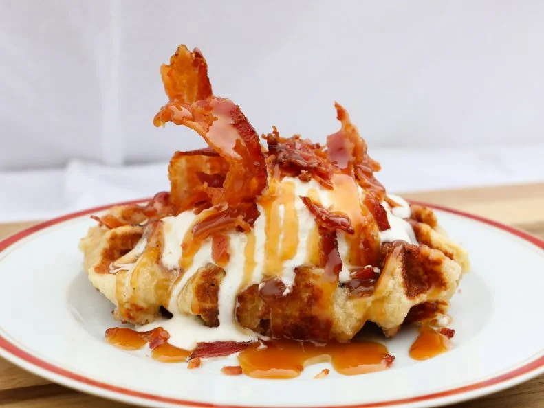 In 2004, Bruges native Pierre Vandamme took to Main Street to sell liege waffles based on an old family recipe. His vending cart was such a success, Vandamme teamed up with two more  Belgian natives, expanding the business to a fleet of roving trucks and storefronts in downtown Salt Lake City and Provo. As their first semi-savory addition to the menu, the trio conjured up the Pig on a Cloud, a crunchy liege waffle adorned with whipped cream, caramel sauce and sizzling strips of bacon.