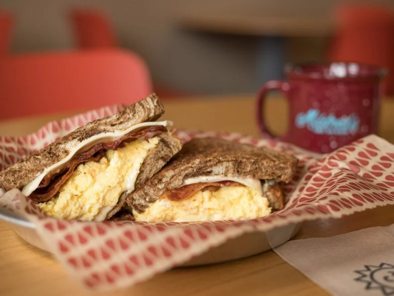There are so many ways a well-intentioned breakfast sandwich can go wrong — improperly timed eggs, unbalanced ratios, sloppy composition. But the sammies at Mildred’s Coffeehouse are basically flawless. Their secret? They flash steam their eggs. Yes, Mildred’s has not one but two espresso machines—one for coffee of course, and a second machine in the kitchen solely for steaming eggs. There’s no butter or oil involved. In fact, the special process requires no additional fat whatsoever. The end result is a feather-light and fluffy scrambled eggs that are ideal in a sandwich. The Standard Breakfast Sandwich, known to many as the ultimate breakfast sandwich in Kansas City, is the perfect delivery vessel. The steamed eggs join forces with bacon, American Swiss and pepper-dijon mayo on a choice of wheat, sourdough, marble rye, jalapeno bread or ciabatta.
https://www.mildredskc.com