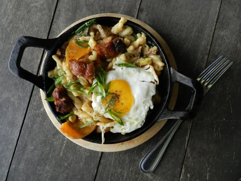 With its location in a restored 19th-century barn on Traders Point Creamery’s organic dairy farm, The Loft Restaurant has a steady supply of artisan cheeses close at hand, which Chef Toby Moreno showcases in multiple preparations. Moreno transforms mac and cheese into a hearty breakfast meal by adding farm-raised pork belly, green onions and a sunny-side egg to gemelli pasta drenched in a three-cheese Mornay sauce. All three cheeses — cheddar, mozzarella, and Monterey jack — are crafted by a team of Traders Point Creamery’s cheesemakers in the barn’s lower level. This breakfast mac pairs nicely with the Bloody Mary made with organic vodka, tomato juice, freshly ground horseradish and hot sauce, and garnished with a pickle, olive and piece of cheese. Other standout options on The Loft’s seasonal American menu include the roasted mushrooms, leeks and squash, as well as the corn, roasted cabbage and spinach.