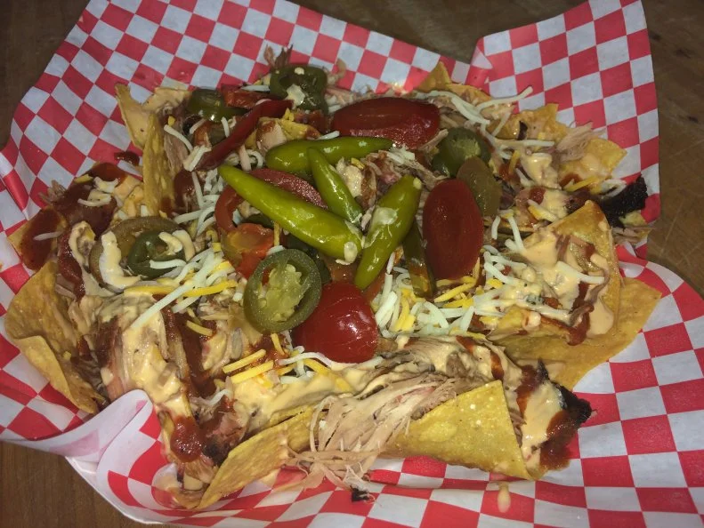 If the walls could talk, Rebel Barn’s former life as a drive-through beer barn would have some colorful stories to tell. These days, it’s home to a from-scratch barbecue joint where the food does all the talking. Everything from the Delta-style tamales to the slow-smoked meats are cooked outside on a rotisserie cooker over hickory and pecan wood. This technique imbues the meats with a distinctly smoky flavor that’s tailor-made for pairing with cheese. Want a taste of this addictive combination? Order the barbecue nachos, which come smothered in a rich cheese sauce made from a tightly guarded recipe. These are not your stadium concession nachos: White corn tortilla chips are fried to order, then heaped onto a plate, drenched with that secret cheese sauce and piled with your choice of pulled pork, smoked chicken or beef brisket. The whole lot is slicked with sweet-smoky barbecue sauce, then topped with shredded cheese and a trio of cherry red peppers, sliced jalapenos and whole Mississippi short peppers. It all adds up to a smoky, cheesy, spicy bite that will likely set tongues wagging — in a good way. 