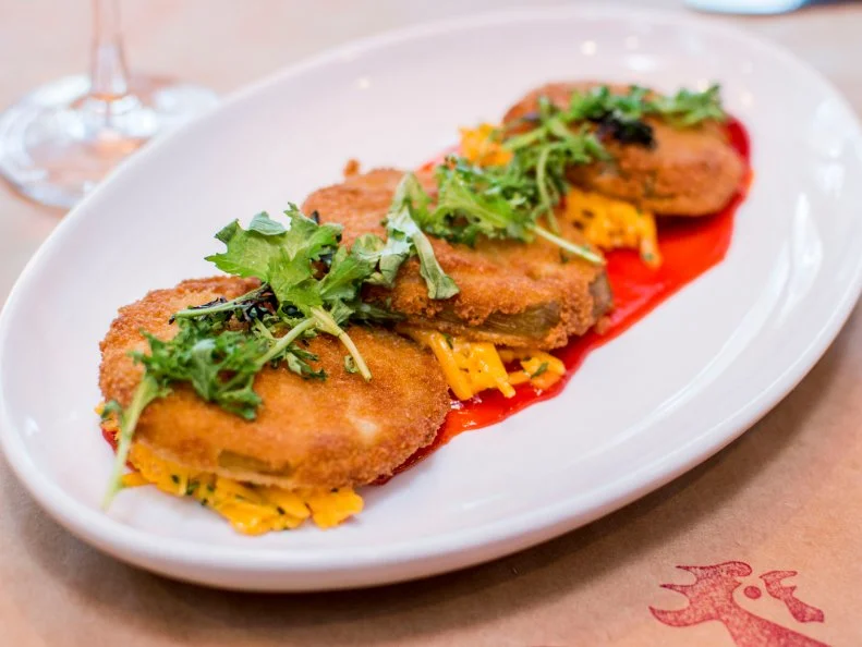 At his Hilton Head Island bistro, Chef-Owner Clayton Rollison offers a Southern-accented menu of seasonal American fare. One of his favorite creations featured at Lucky Rooster is a refined take on a classic Southern combo: pimento cheese and fried green tomatoes. For the cheese-mayo spread, Rollison follows tradition by combining grated sharp cheddar and Duke’s mayonnaise, then veers off course by kicking it up with pickled jalapenos, pickling juice, Worcestershire sauce and Tabasco sauce. Sliced green tomatoes are breaded with Panko and fried to order, then plated atop generous dollops of the creamy, cheesy spread and served with spicy red pepper jam and chow chow. This knife-and-fork affair tastes best if you get some pimento and crisp-crusted tomato in every bite.