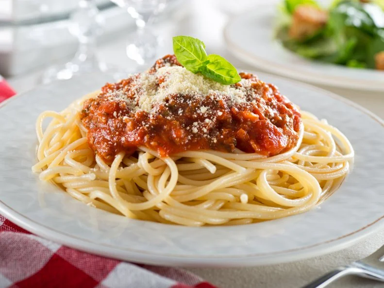 A plate of delicious spaghetti bolognese with meat sauce and fresh basil.