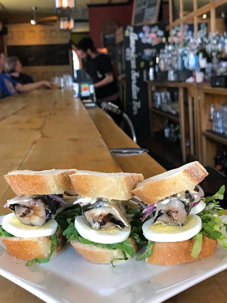 The enormous sculpture of a half-peeled sardine can dangling above ASB’s front door serves as a signpost of sorts, reminding passersby of the briny delicacies that await at this Point Breeze pub. Chef Doreen DeMarco always runs a selection of the little fish on the menu, prepared in various ways with various accompaniments. But one standout is the sardine sandwich: primo Galician canned sardines, sliced pickled egg, lettuce, onion and dijonnaise tucked between two small hunks of a hoagie roll. It’s a two-bite delight, logically priced at $2.