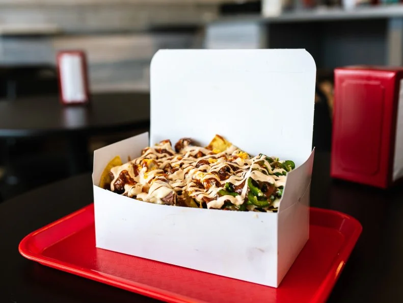 Pitmaster/Chef Ben Welch turns out a beastly portion of BBQ Nachos at Big Baby Q’s, so either bring your crew or bring home leftovers. The white takeout box can barely contain this stack of corn tortilla chips slathered with housemade pepperjack queso, drizzled with BBQ sauce and piled with baked beans, chipotle sour cream, candied jalapenos, shredded cheddar and your choice of meat. Welch customizes each order with turkey, pulled pork or brisket (he’s known for his brisket). No matter which you choose, it’ll only cost you $10. 
