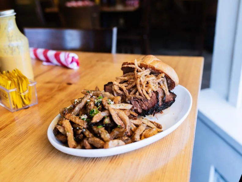Load up on St. Louis-style barbecue for less at Salt + Smoke. Known for its bourbon and BBQ, this spot serves a prime brisket sandwich for $10.95. Pro move: when given the option of lean or fatty brisket, ask for burnt ends. Doing so will get you a brisket sandwich slathered with burnt end mayo and piled with crisp tobacco onions. Go all in with a side of garlic and herb fries.