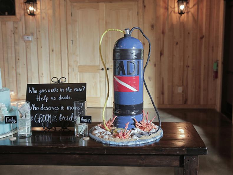 As seen on Food Network's Dallas Cakes, a groom's scuba tank-themed cake is set up and ready for prime time at a wedding reception. Surrounding the base of the cake is coral, seashells, and gauges made of fondant. They all sit atop a bed of crushed graham craker to give the look of a sandy beach.