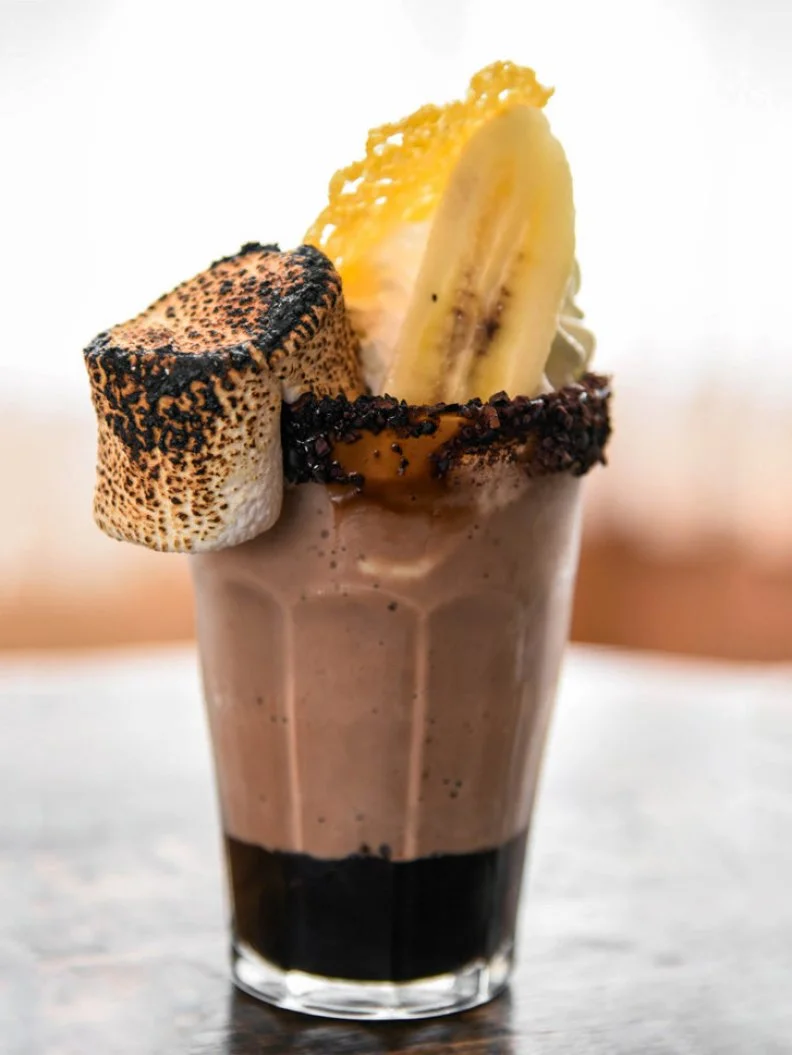 Itâ  s obvious that the city home to Kentuckyâ  s Urban Bourbon Trail would want to put the local distilled liquid in just about anything, including this slurpable frozen treat. Milk, bourbon and chocolate ice cream are blended together and served in a cocoa nib-rimmed glass with whipped cream, cheddar tuile, caramelized banana and toasted marshmallow.