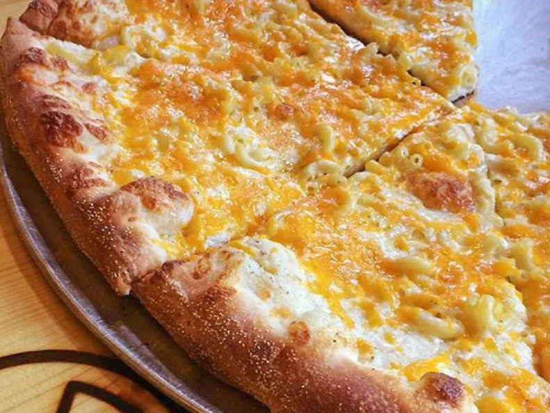 Mac ‘n Cheese, tater tots, smoked brisket: the toppings at this Wisconsin pizzeria sound like they were dreamt up at a late-night party in a college dorm. Whether they were or not, we can’t say for sure. But we do know that you’ll probably find plenty of colorful biodegradable Ian’s boxes in dorm bins on Saturday and Sunday mornings. The place serves more than a dozen quirky specialty pies, all of which are sold in 12-, 16- and 20-inch pies, as well as by the slice. That’s what makes it a favorite among local students at University of Wisconsin-Madison, who scarf down comforting creations like the signature Mac ‘n Cheese slice or the Drunken Ravioli, which combines vodka sauce, Mozzarella, Asiago, and yes, actual cheese ravioli.