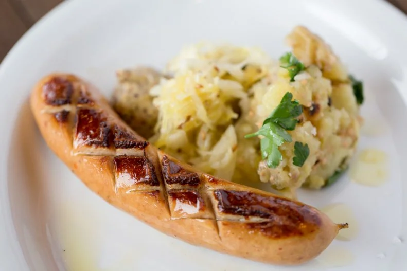 For a few bucks, you could get a hot dog floating in dirty water from a street vendor to eat while walking. For a few more, you can sit down at Olympia Provisions Public House near an indoor fire with a knife and fork, and tuck into your choice of artisanal bratwurst, cheese-filled sausage, kielbasa, pork or beef frankfurter, or French garlic sausage from renowned salumist Elias Cairo, plus sauerkraut, warm potato salad and whole-grain mustard ($9). And for about the price of a soda, you can get a 16-ounce lager to wash it all down.