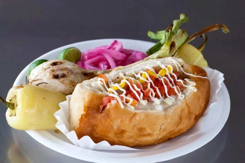 Perhaps one of the original over-the-top hot dogs, the Sonoran is imitated across the country but remains the most authentic in its hometown of Tucson. El Guero Canelo’s version, served in a bolillo, is wrapped in bacon and topped with a hearty scoop of pinto beans, tomatoes and onions before it gets drizzled with ketchup, mustard, mayo and jalapeno sauce across the top.