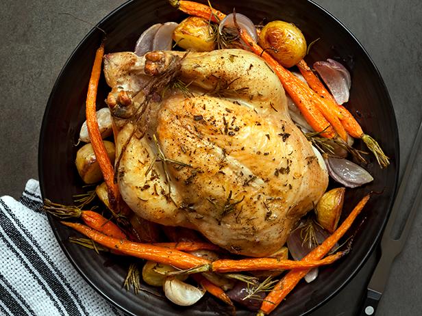 Roasted chicken dinner with vegetables and herbs.  Overhead view.