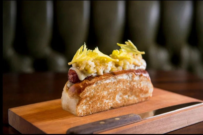 If acclaimed chef Daniel Humm is going to put his name on a hot dog, you know it has to be filled with only the finest ingredients. This decadent dog is wrapped in bacon and topped with melted Gruyère cheese. It is then topped with a celery relish with mustard seeds and a bit of black truffle. For a final flourish, it gets a dollop of truffle mayonnaise before it lands comfortably in a rich and buttery brioche bun. 