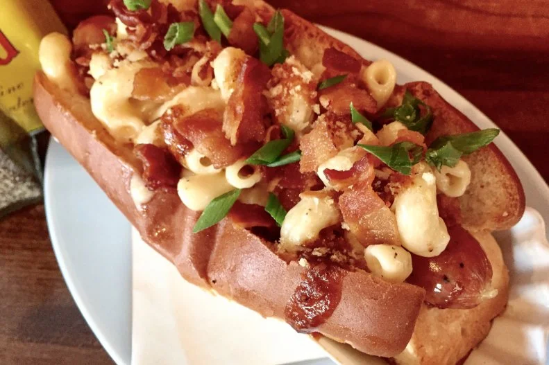 Expect all-American hot dogs with a Lonestar State twist at this Houston weenie shop. Toppings include fresh guacamole, refried black beans, brown sugar-baked ham, and beef and chorizo chili. One of the top-sellers is the Rodeo Dog, created by Chef-Co-owner Amalia Pferd during Houston’s rodeo season. It features an all-beef dog smothered in creamy cheddar mac & cheese, barbecue sauce, bacon, scallion and parmesan breadcrumbs inside a buttery split-top bun. “It’s everything that is comforting about the south and also a little tangy just like Texas,” says Pferd.